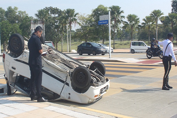 PEGAWAI Penyiasat, Inspektor Mohamad Khirul Anuwar Ahamad memeriksa kenderaan yang terbalik akibat dirempuh di Lebuh Saujana di sini baru-baru ini.