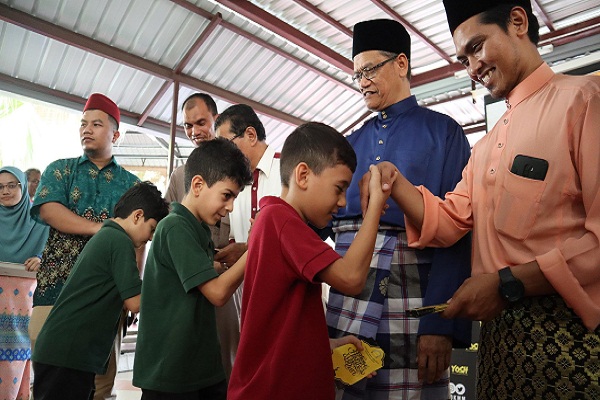 SHAHRUDDIN (tengah) menyampaikan duit raya kepada anak-anak Syria pada majlis anjuran YOSH di Surau Al- Furqan. Presint 11, Putrajaya baru-baru ini.