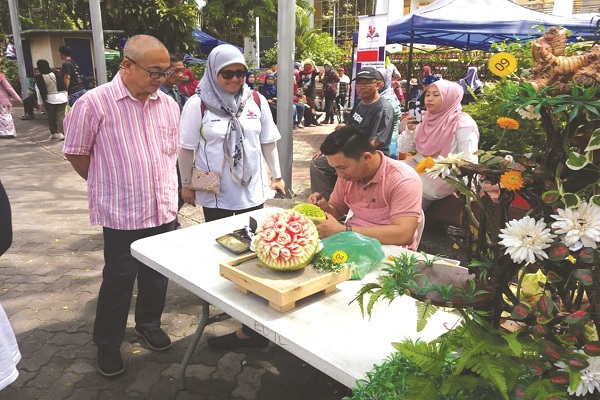 AHLI Parlimen Labuan, Datuk Rozman Isli (kiri) melihat salah satu hasil ukiran buah yang ditampilkan seorang peserta.