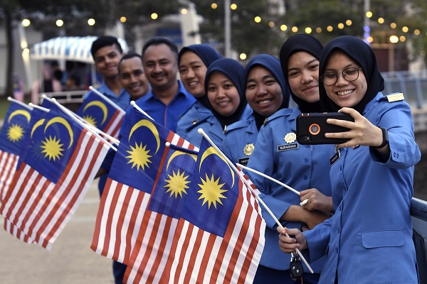 ANGGOTA Angkatan Pertahanan Awam berswafoto bersama rakan-rakan sambil mengibarkan Jalur Gemilang.