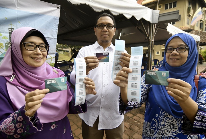 PENDUDUK menunjukkan pelekat barkod dan kad Mesra Petronas.