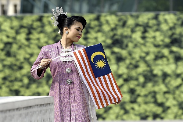 SEORANG gadis berpakaian kebaya songket bergambar bersama Jalur Gemilang.